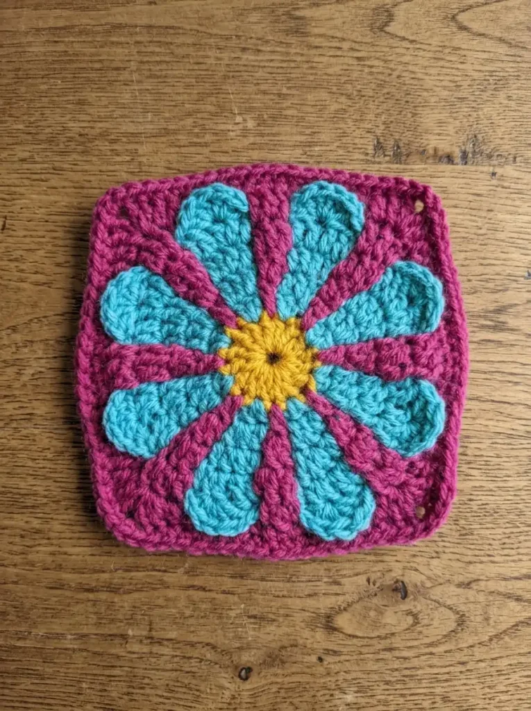 step 6: finished square, front view showing completed daisy]