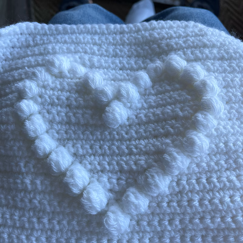 Close-up view of Bobble Heart Crochet Blanket showing 3D bobble stitch texture and heart motif.