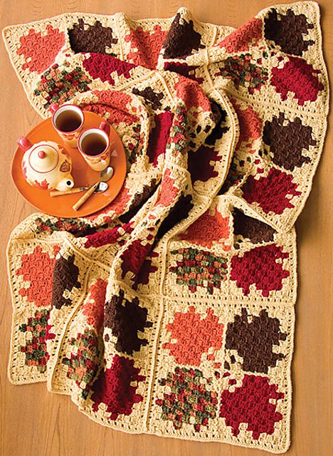 Crochet afghan with leaf-shaped motifs in green, rust and gold