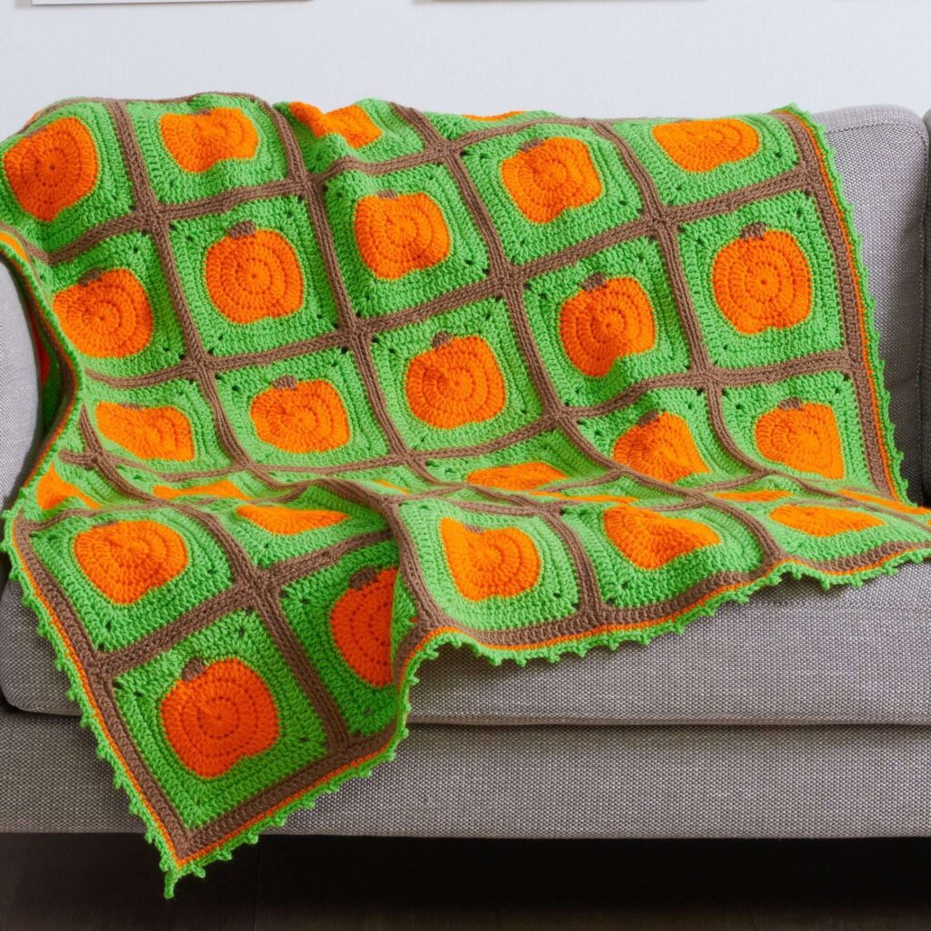 Crochet blanket with pumpkin appliques, perfect for Halloween and Thanksgiving