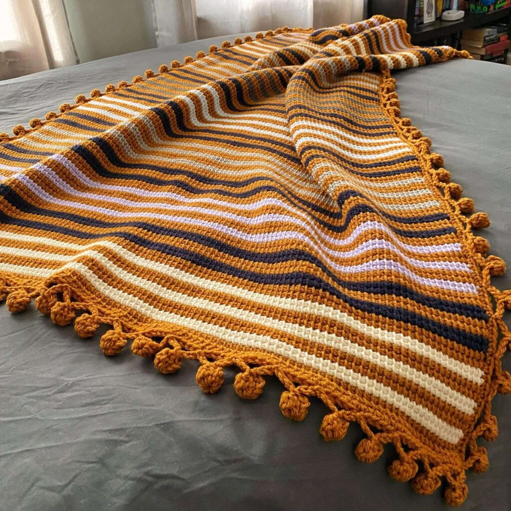 Textured crochet blanket made with a structured Tunisian stitch pattern in neutral colors