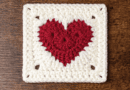Crochet heart granny square pattern with red heart center and white border displayed on a wooden background