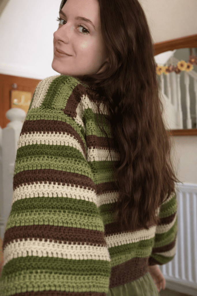 Modern crochet sweater jumper made with simple textured stitches, showcasing striped design, ribbed edges, and cozy handmade style in a natural outdoor setting.