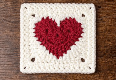 Crochet heart granny square pattern with red heart center and white border displayed on a wooden background
