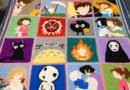 Handmade anime crochet blanket with pixel-style character squares, Ghibli inspired design, black borders and vibrant colorwork panels displayed on wooden floor.