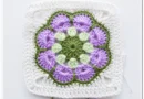 African flower granny square finished showing complete floral motif in pink blue teal and cream
