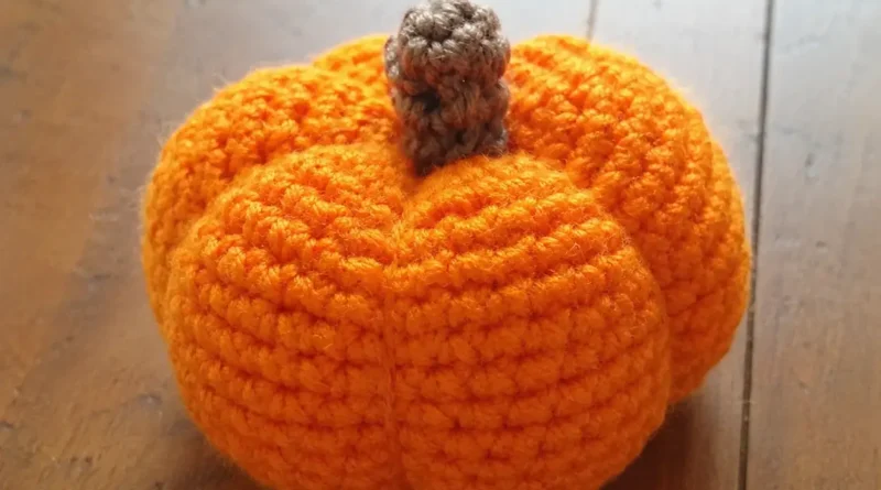 Crochet pumpkin pattern free — finished orange amigurumi pumpkin with brown stem on wooden table