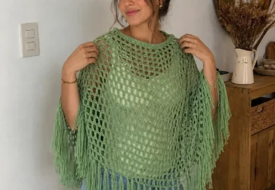Woman wearing a lightweight mesh crochet poncho in neutral colors outdoors.