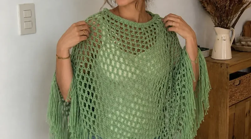 Woman wearing a lightweight mesh crochet poncho in neutral colors outdoors.